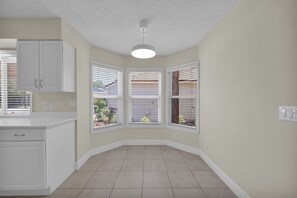 A kitchen with white cabinets, a white countertop, a ceiling fan, and a bay window with blinds. - Sawgrass TPC golf views (Sawgrass)