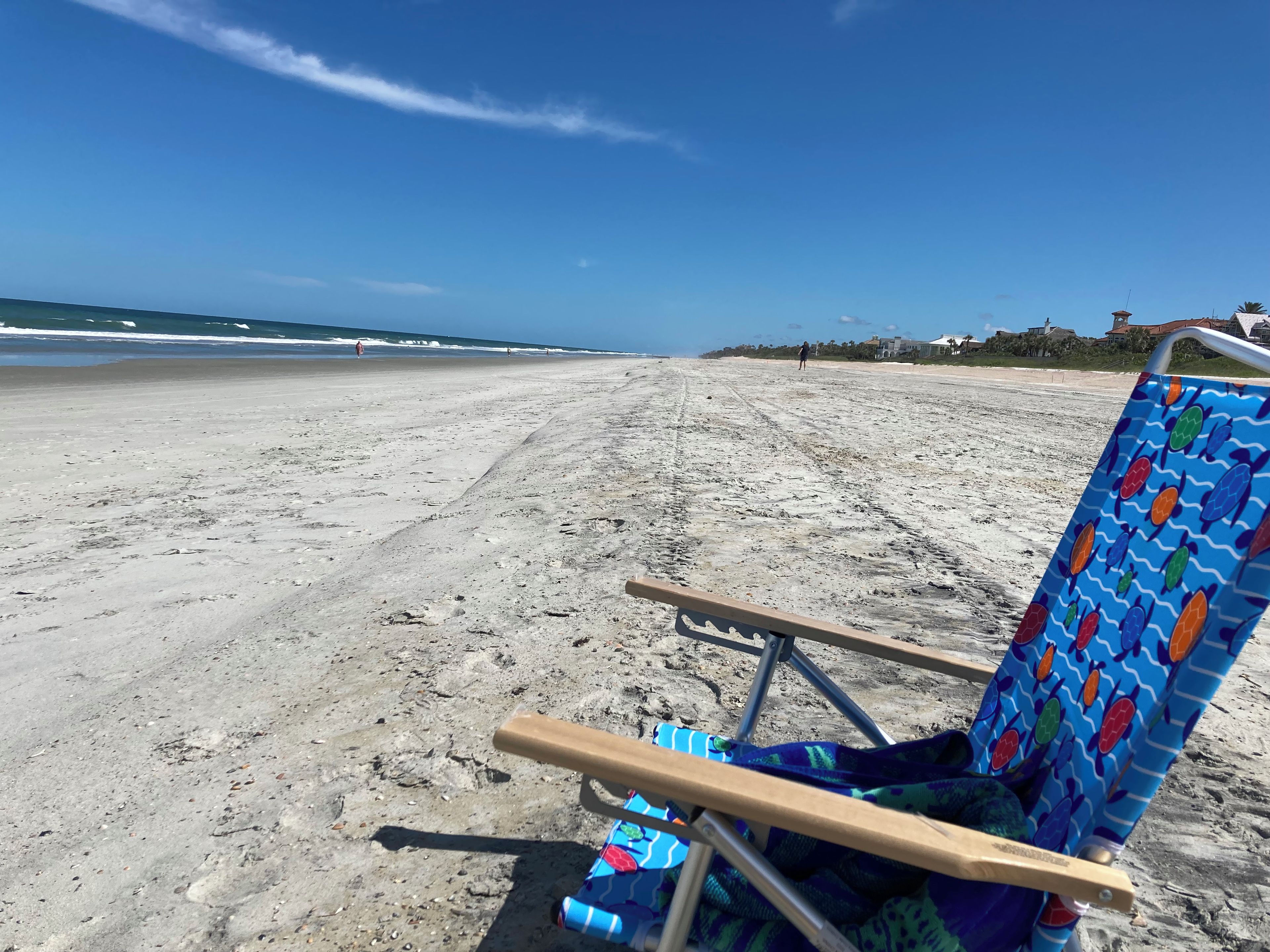Une plage avec une seule chaise longue et une serviette aux couleurs vives.