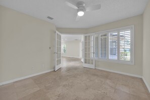 A spacious room with a high ceiling, a ceiling fan, and large windows with blinds. - Sawgrass TPC golf views (Sawgrass)