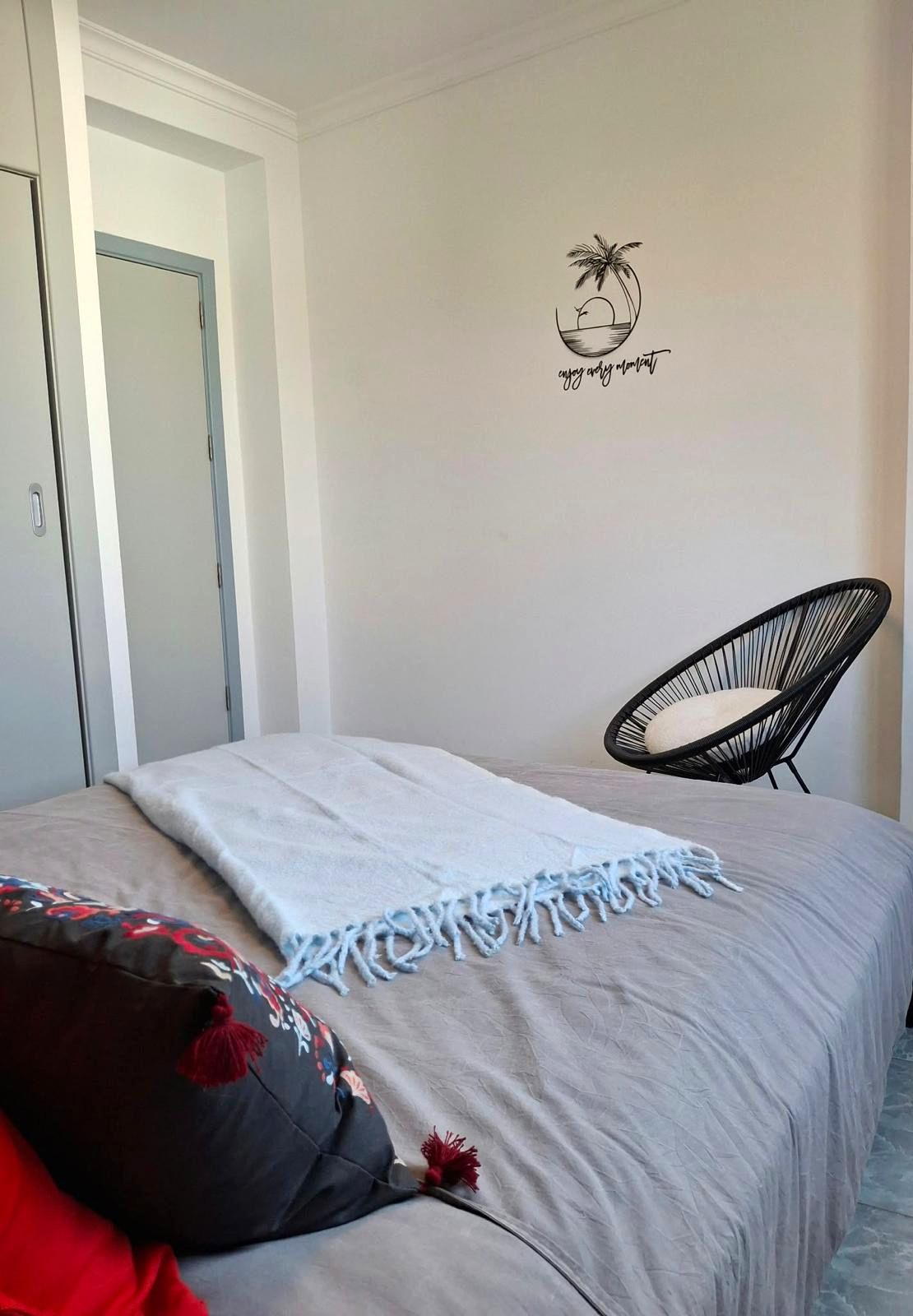Un dormitorio con cama, una silla, una puerta y un adorno en la pared.