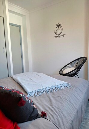A bedroom with a bed, a chair, a door, and a wall decoration.