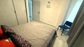Ein Schlafzimmer mit einem Bett, einem Sessel, einer Tür und einer Wand mit einem Logo.
