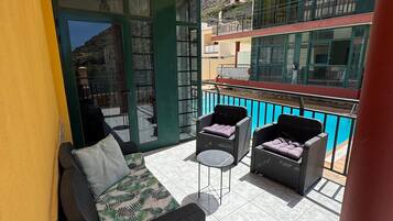 Un balcón con un sofá, dos sillas y una mesa.