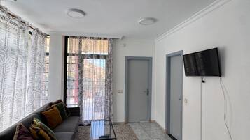 Een moderne woonkamer met een bank, een salontafel en een aan de muur bevestigde televisie.