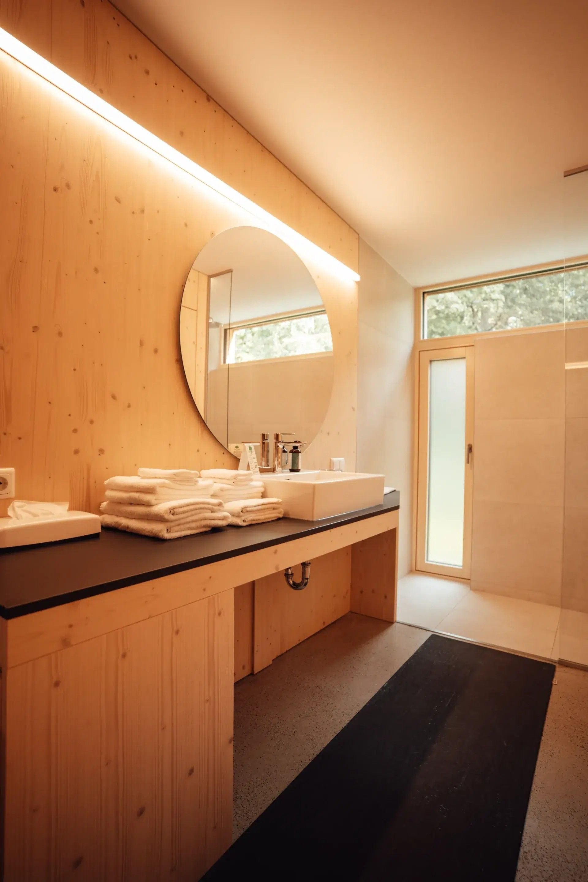 A modern bathroom with a wooden vanity, a large mirror, and a sink.