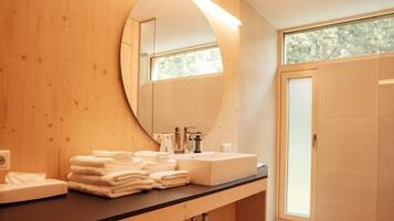 A modern bathroom with a wooden vanity, a large mirror, and a sink.