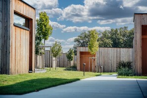 A modern building with a wooden facade, a clear sky, and a well-maintained lawn.