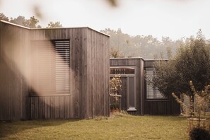 Un edificio moderno de madera con ventanas amplias y un patio cubierto de césped.