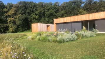 Een modern gebouw met een houten gevel, een gazon en diverse planten en bloemen.