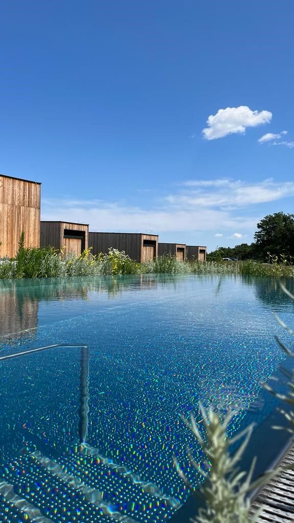 Una piscina infinita con un edificio de madera al fondo.