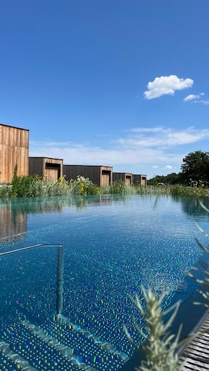 An infinity pool with a wooden building in the background.