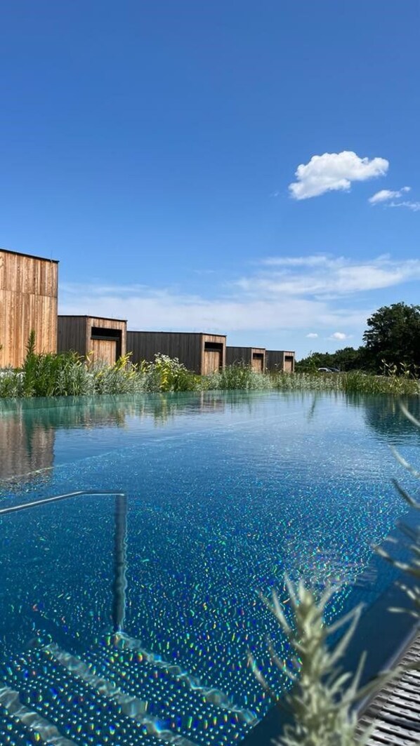 An infinity pool with a wooden building in the background.