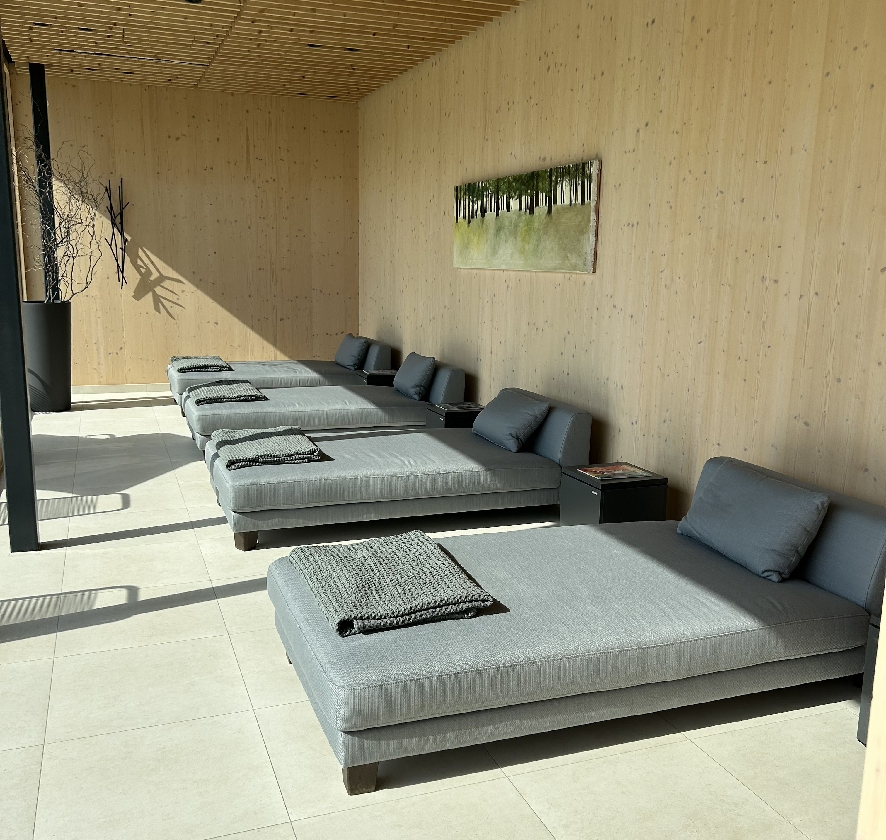 A modern spa room with multiple grey sofas and a large window.