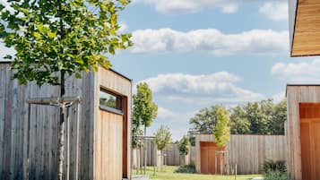 Un espacio exterior moderno con estructuras de madera, un camino de hormigón y cielo despejado.
