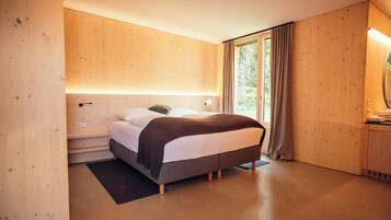 A modern bedroom with a bed, wooden walls, a window with curtains, and a built-in wardrobe.