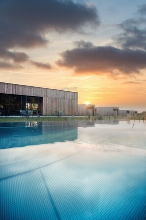 Un edificio moderno con piscina, ventanas amplias y vista al atardecer.
