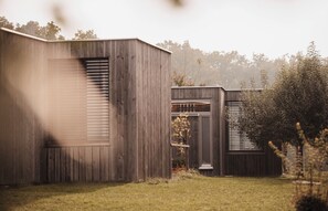 Un edificio moderno de madera con ventanas amplias y un área verde al frente.