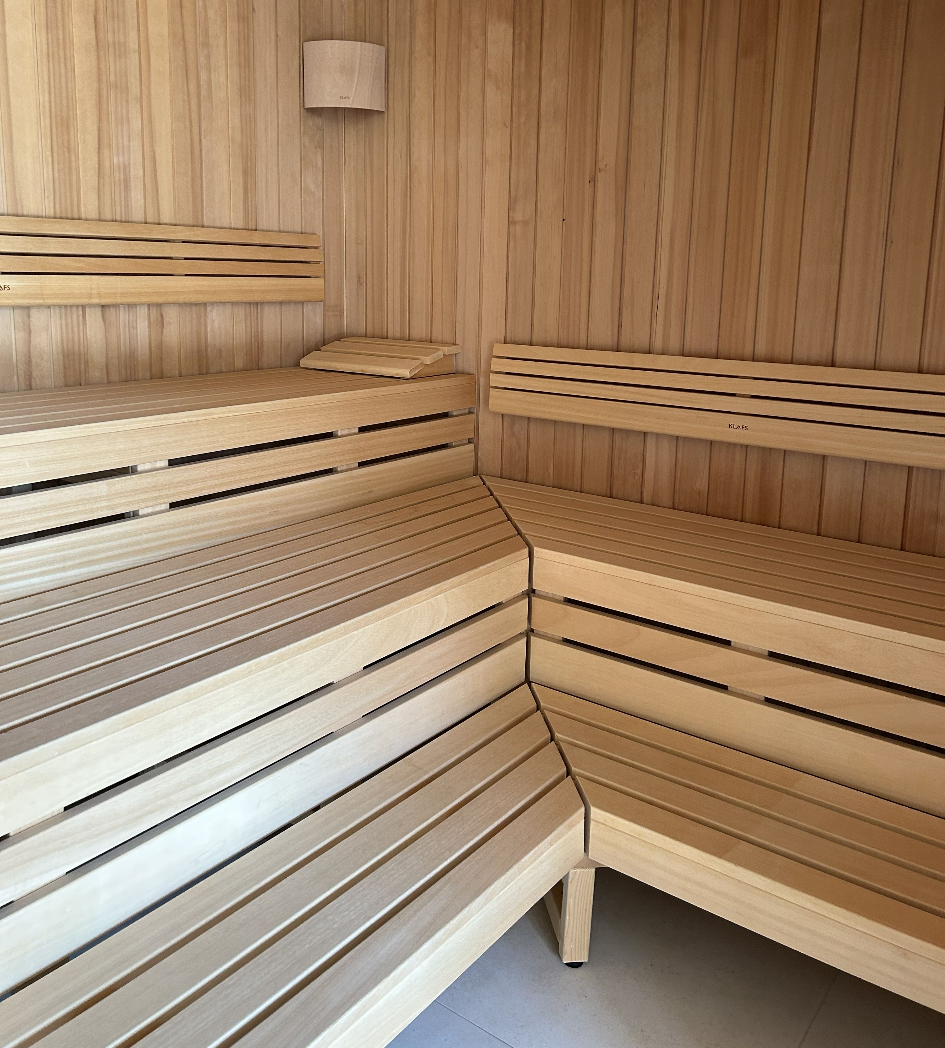 Una sauna con bancos de madera y un calentador en la pared.