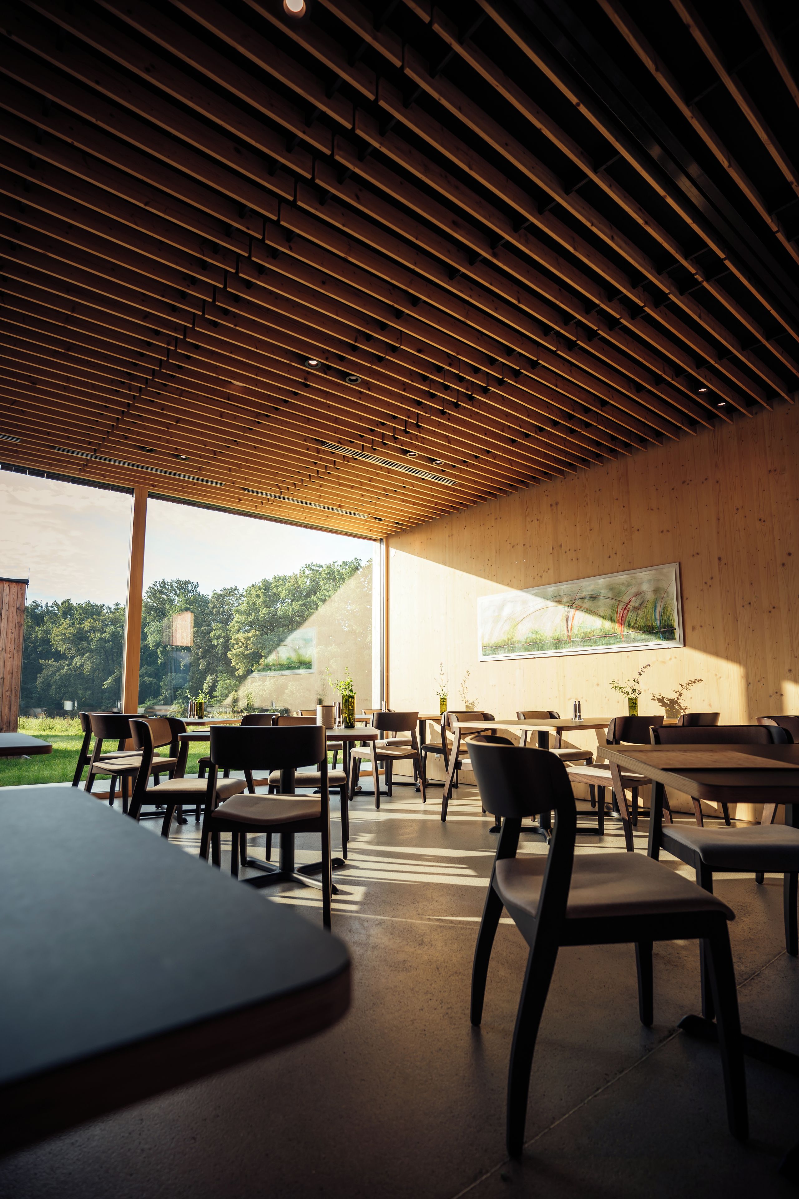 Un comedor interior con techos de listones de madera, mesas y sillas.