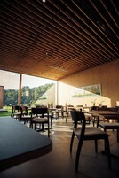 Un comedor interior con techos de listones de madera, mesas y sillas.