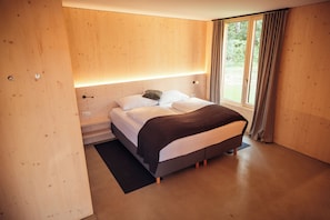 A modern bedroom with a bed, a bedside table, a nightstand, and a window with curtains.