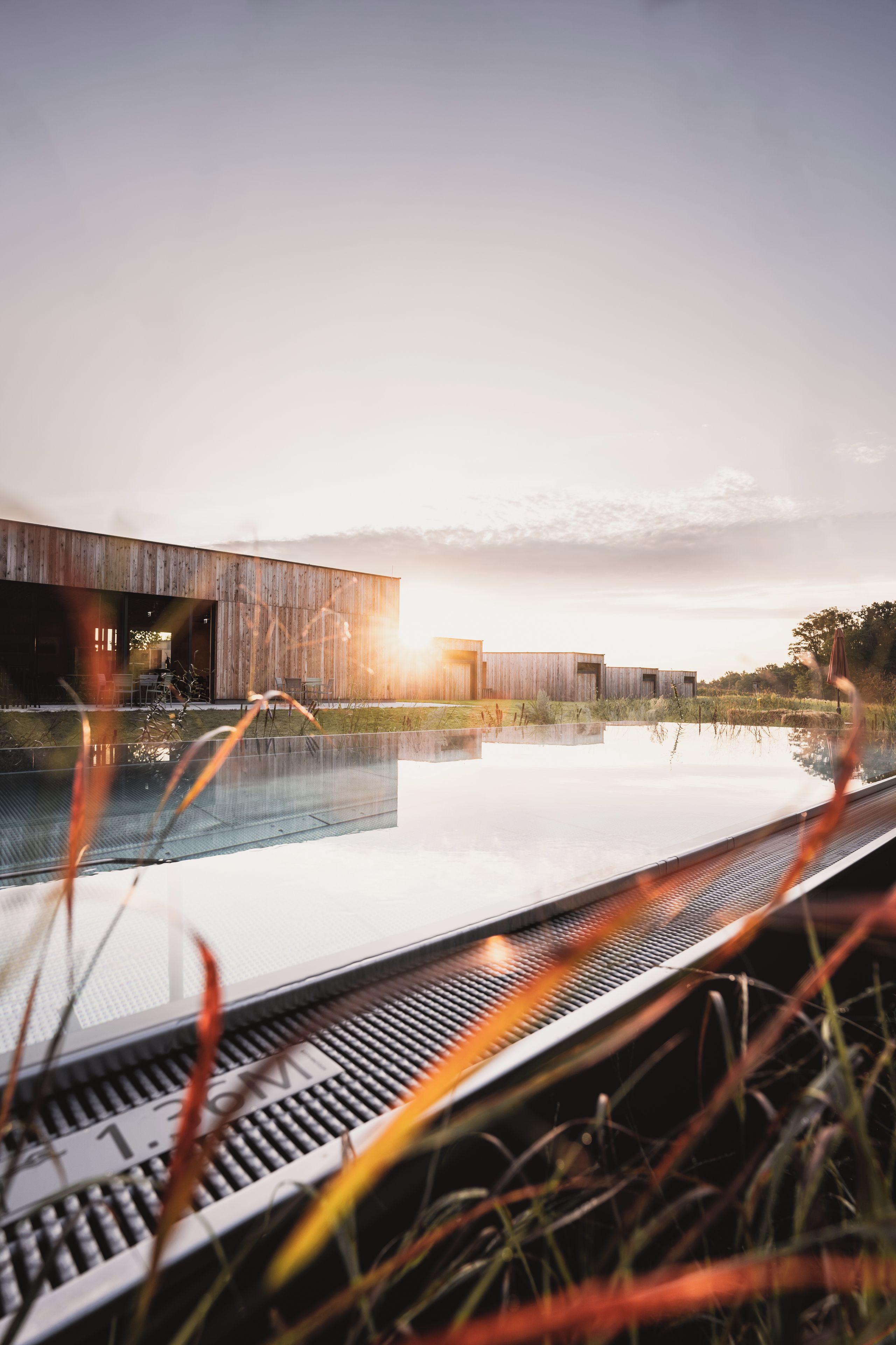 Un edificio moderno con piscina, rodeado de césped y árboles.