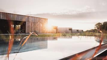 Un edificio moderno con piscina, rodeado de césped y árboles.