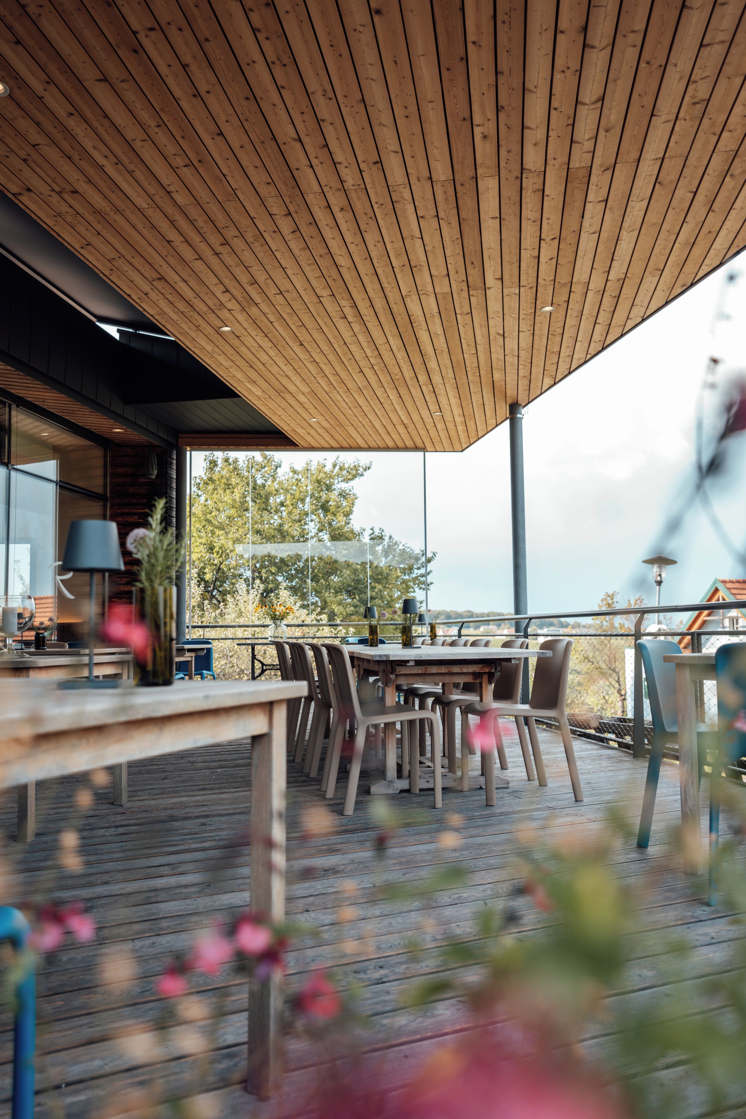 Un área de comedor al aire libre con techo de madera, mesas y sillas.