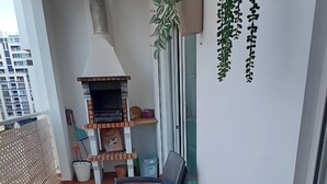 A balcony with a table and chairs, a grill, and potted plants. - Sulaosol Apartment with Shared Pool, Wi-Fi, and Air Conditioning (Portimão)