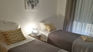 A hotel room with two beds, a bedside lamp, and a painting on the wall. - Sulaosol Apartment with Shared Pool, Wi-Fi, and Air Conditioning (Portimão)