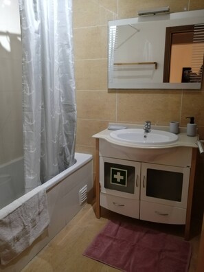 Une salle de bain équipée d’une baignoire, d’un lavabo, d’un miroir et d’un meuble orné d’un symbole médical.