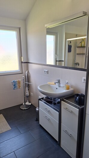 Ein modernes Badezimmer mit großem Spiegel, Waschbecken und Dusche.