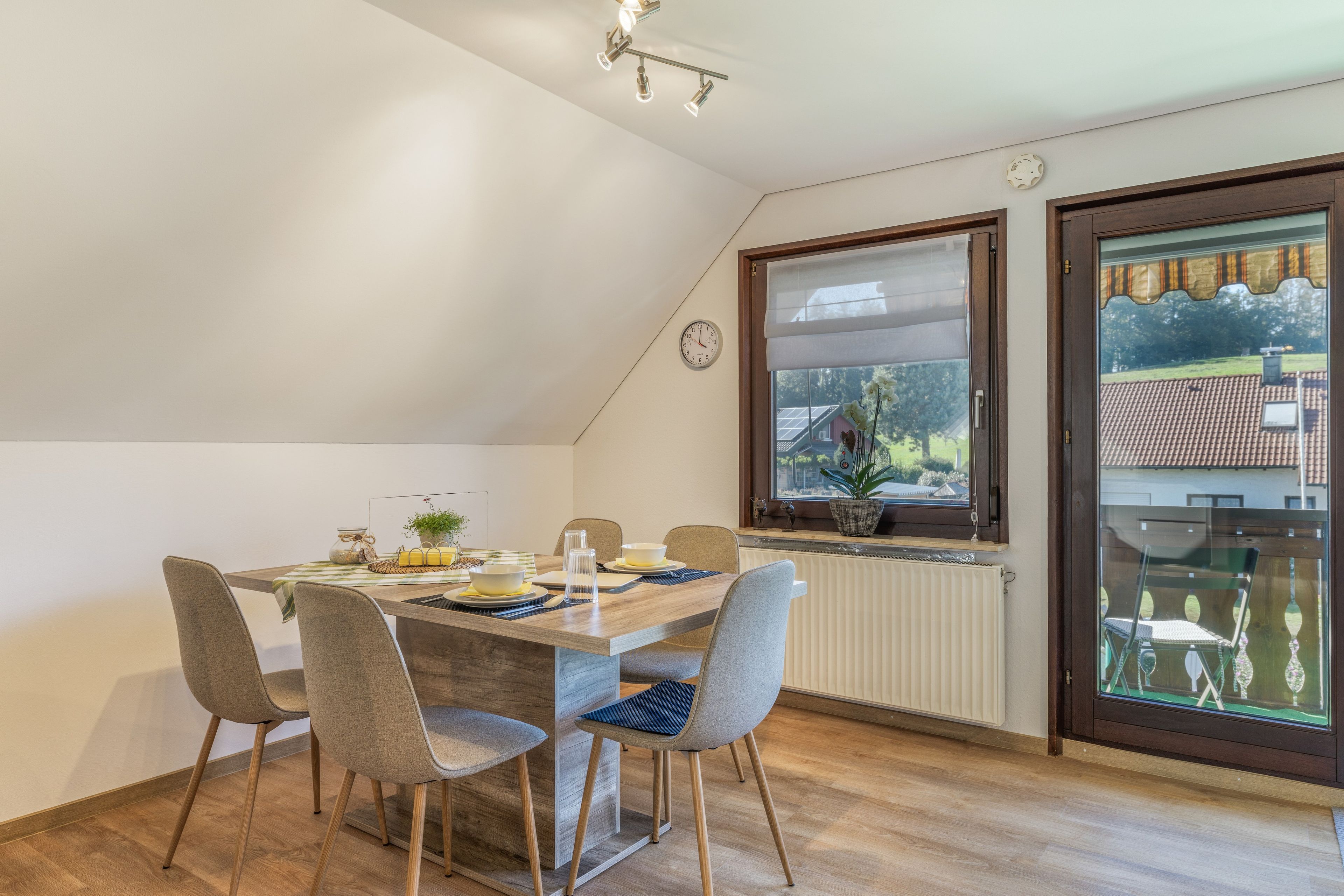 Ein Essbereich mit einem Tisch für vier Personen, Stühlen, einem Fenster mit Blick auf ein Haus und einer Heizung.