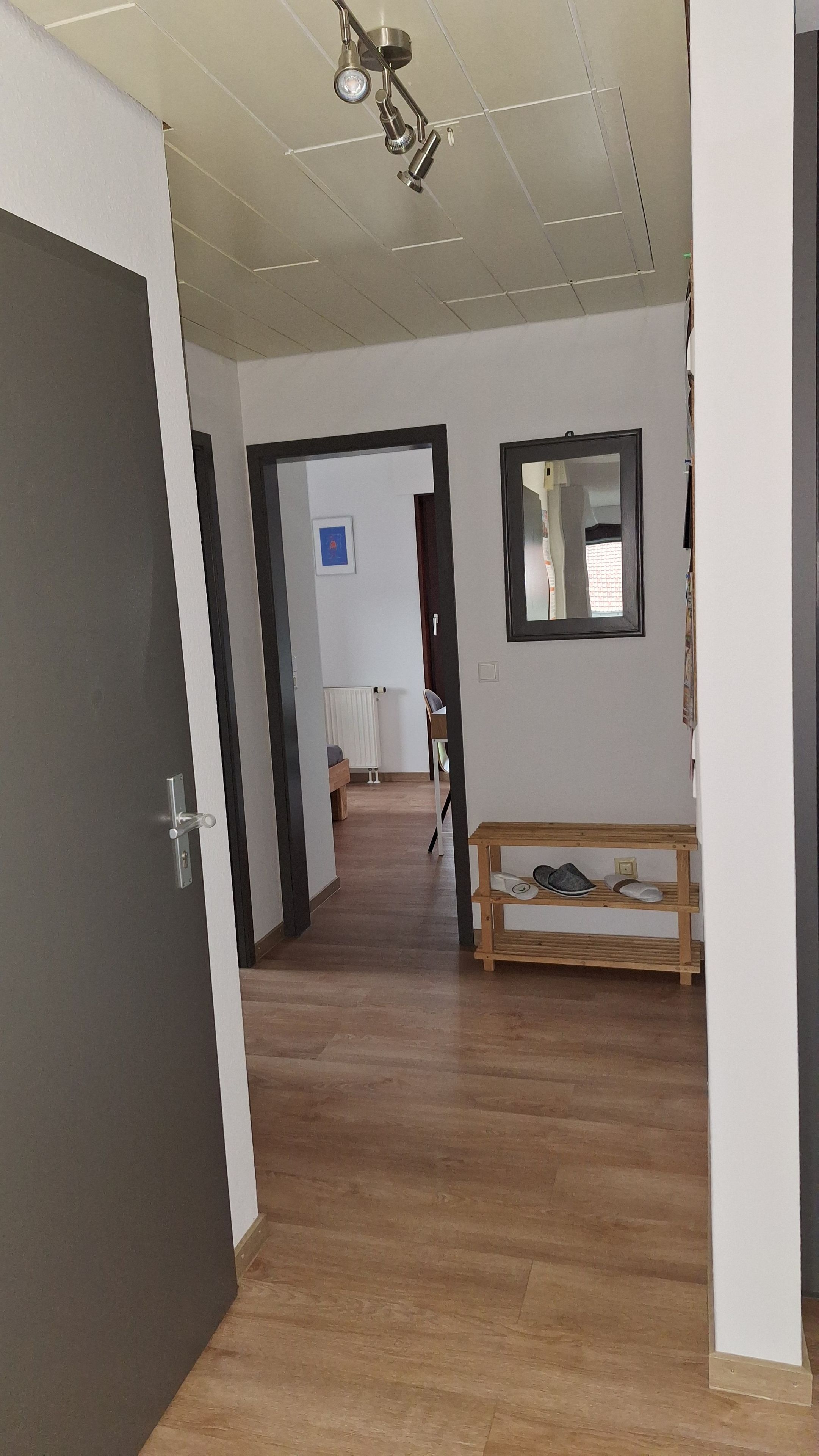 A hallway with a wooden bench, a radiator, and a framed mirror on the wall.