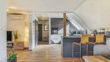 A modern kitchen with a central island, bar stools, and a dining table.