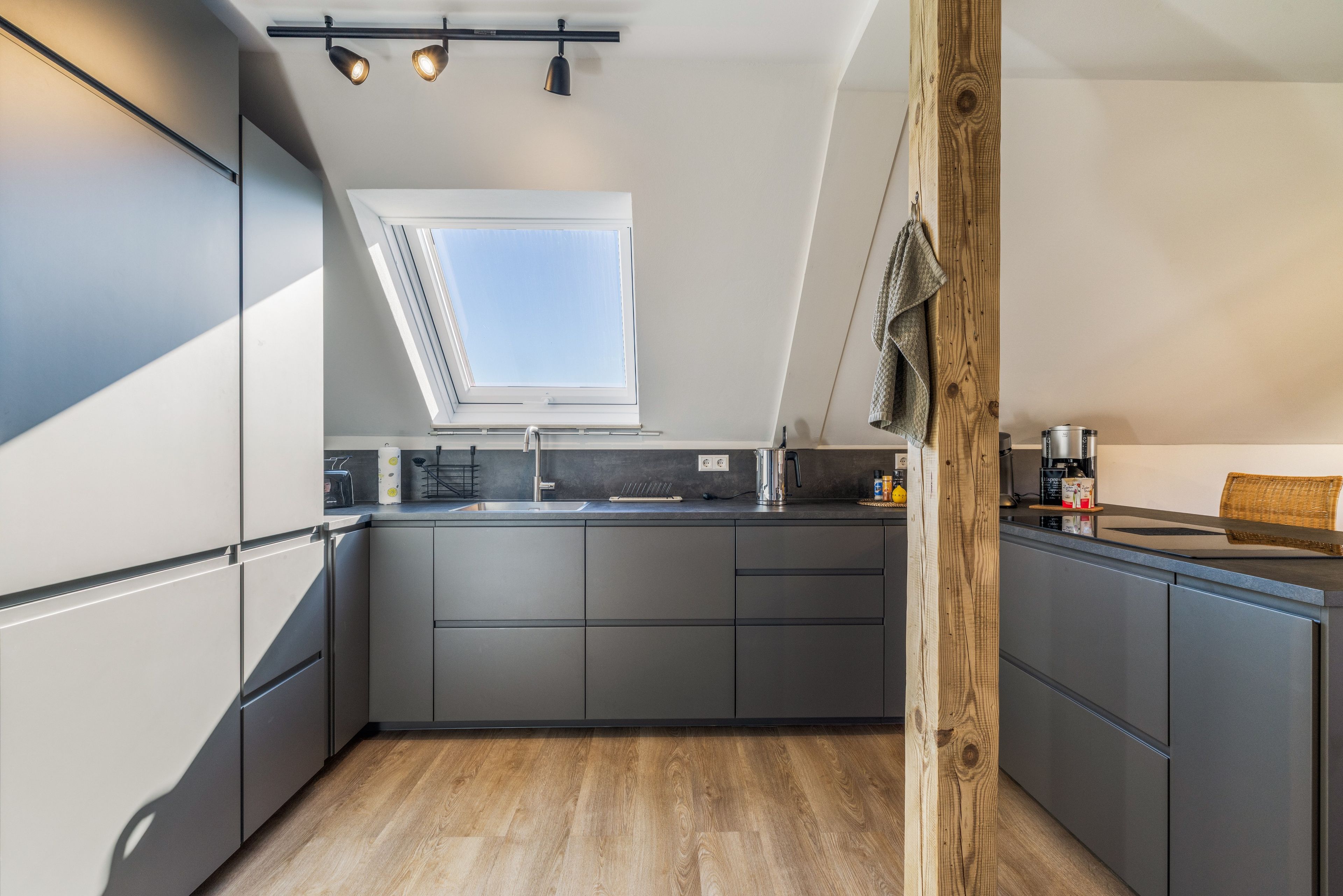 Eine moderne Küche mit Oberlichter, grauen Schränken und Holzboden.