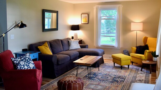 A living room with a sectional sofa, a red armchair, a yellow armchair, a coffee table, and a patterned rug. - 3-bedroom house on a peaceful street on the river in Waldoboro (Waldoboro)