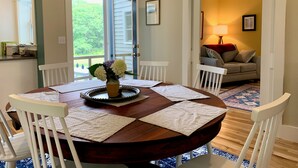 A dining area with a round wooden table, white chairs, and a vase with flowers. - 3-bedroom house on a peaceful street on the river in Waldoboro (Waldoboro)