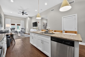 A modern kitchen with a central island, stainless steel appliances, and pendant lighting. - Ivory Summit - Game Day, Concerts & Downtown! (Tuscaloosa)