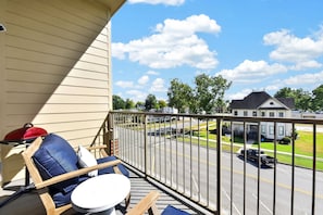 A balcony with a view of a street, a red grill, and a blue chair. - Ivory Summit - Game Day, Concerts & Downtown! (Tuscaloosa)