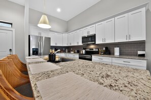 A modern kitchen with white cabinetry, a granite countertop, and stainless steel appliances. - Ivory Summit - Game Day, Concerts & Downtown! (Tuscaloosa)