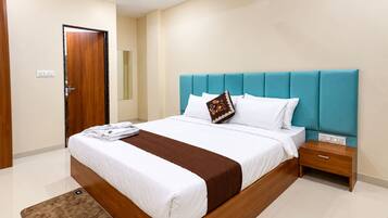 A hotel room with a bed, a nightstand, a ceiling fan, and a wall-mounted light.
