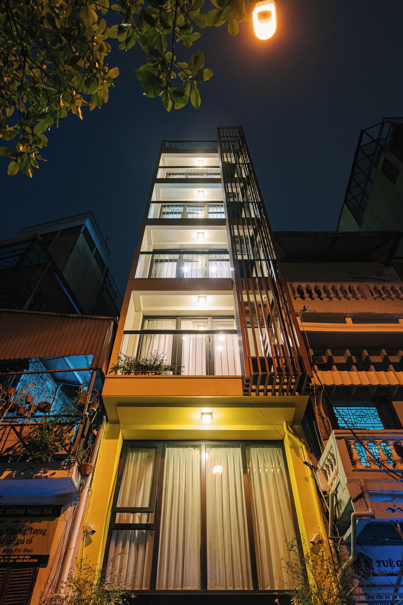 Un immeuble à plusieurs étages doté d’un balcon et d’une enseigne lumineuse au sommet.