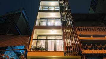 Un immeuble à plusieurs étages doté d’un balcon et d’une enseigne lumineuse au sommet.