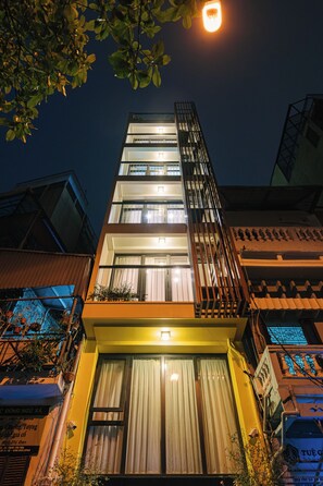 Un immeuble à plusieurs étages doté d’un balcon et d’une enseigne lumineuse au sommet.