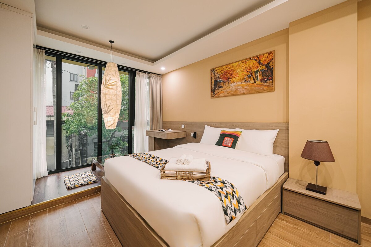 Une chambre d’hôtel avec un grand lit, une table de chevet, une lampe et un tableau au mur.