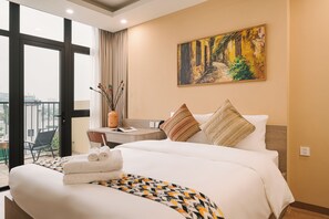 Une chambre d’hôtel avec un lit, un bureau, une chaise, un tableau et une vue sur l’extérieur.
