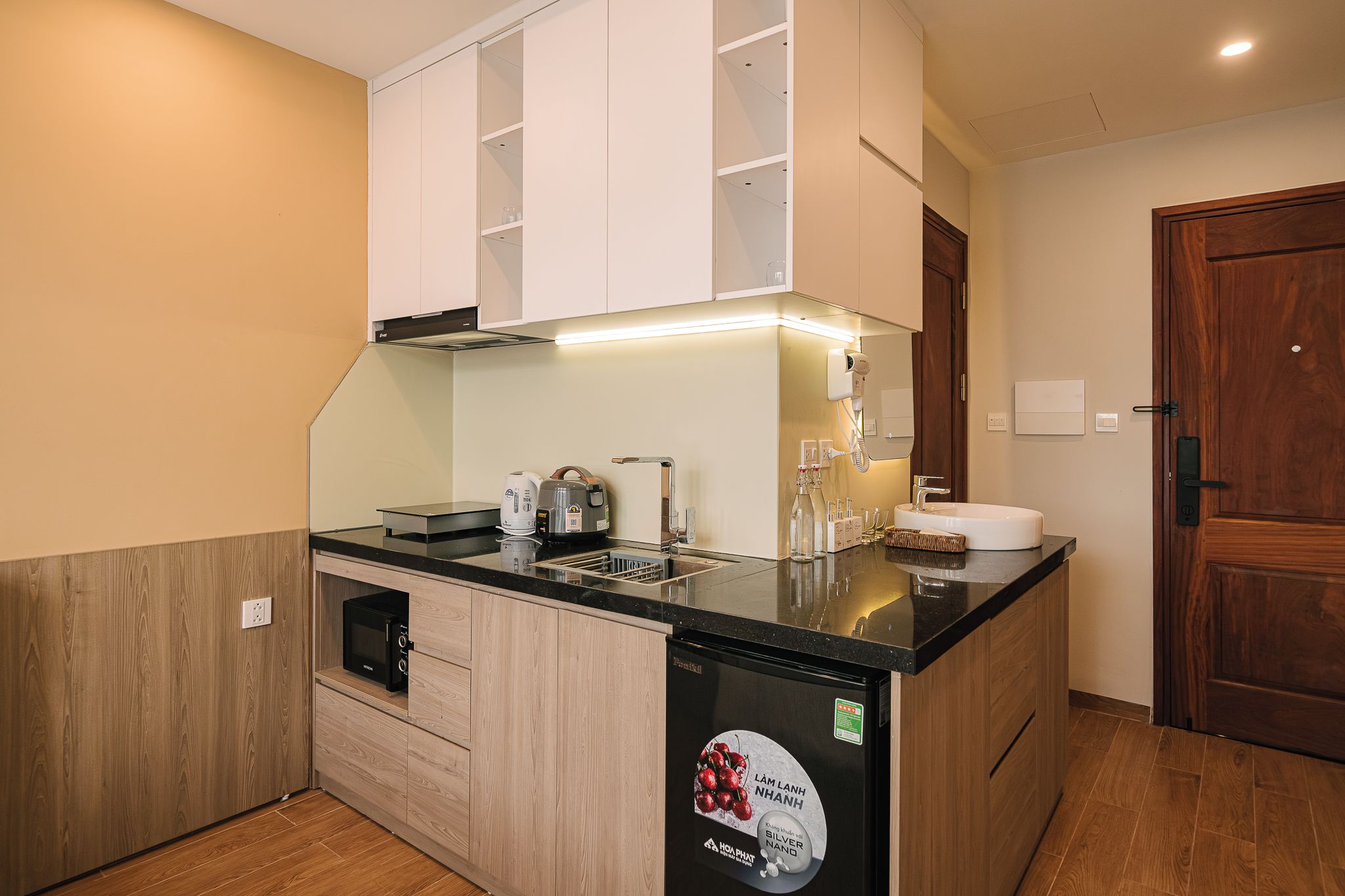 A compact kitchen with a microwave, kettle, and a coffee machine.