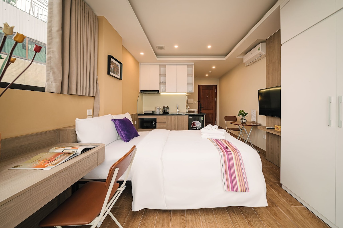 Une chambre d’hôtel comprenant un lit, un bureau, une chaise, une télévision, un coin cuisine et une salle de bain.