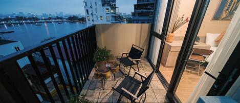Ein Balkon mit Blick auf einen Fluss und die Stadtlandschaft, ausgestattet mit Stühlen und einem kleinen Tisch.